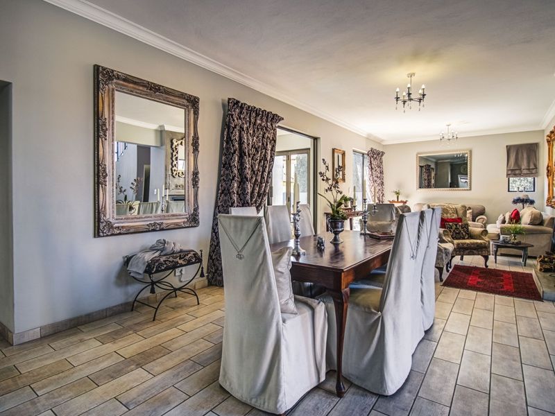 Spacious dining area featuring tiled flooring, elegant cove cornicing, and a fireplace, seamlessly flowing into the adjacent living space.