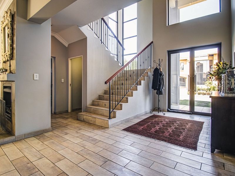 Spacious double-volume entrance hall featuring tiled flooring, a grand staircase with wrought iron balustrades, and a built-in fireplace.