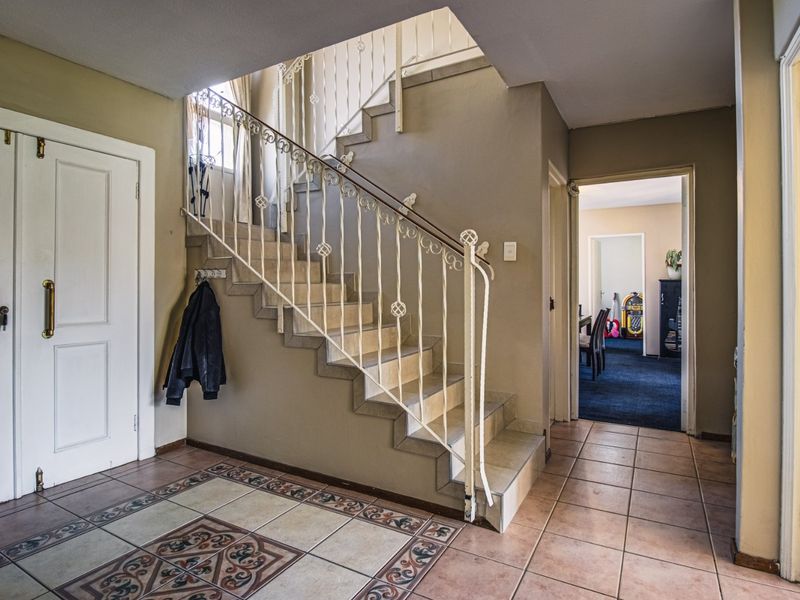 Spacious entrance hall featuring decorative tiled flooring and a classic wrought iron staircase leading to the upper level.