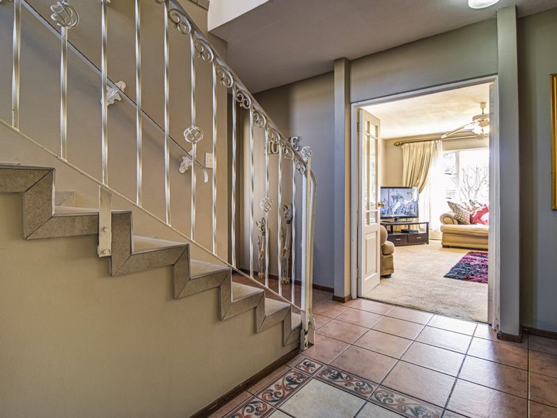 Entrance foyer featuring a decorative wrought iron staircase railing and tiled flooring, providing access to the adjacent living area.