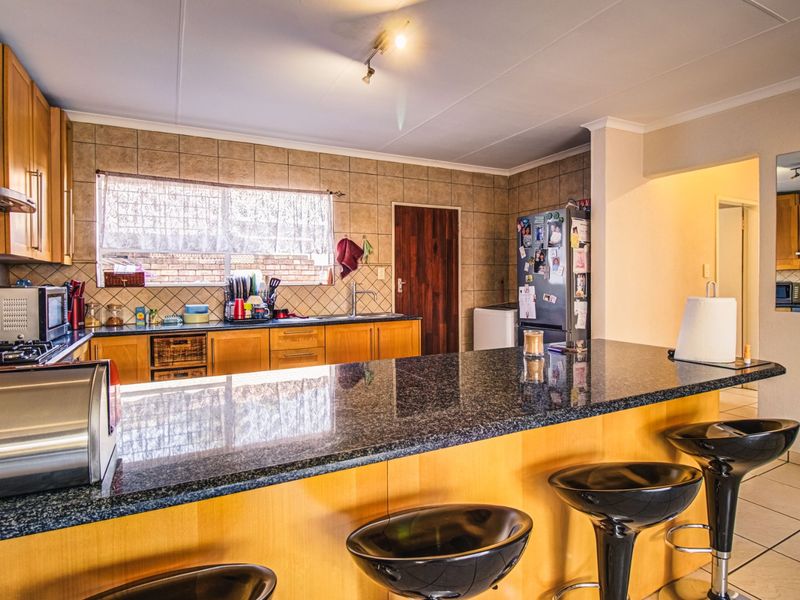 Functional kitchen featuring wooden cabinetry, granite countertops, a breakfast bar, and tiled backsplash, offering a practical layout for daily cooking and dining.