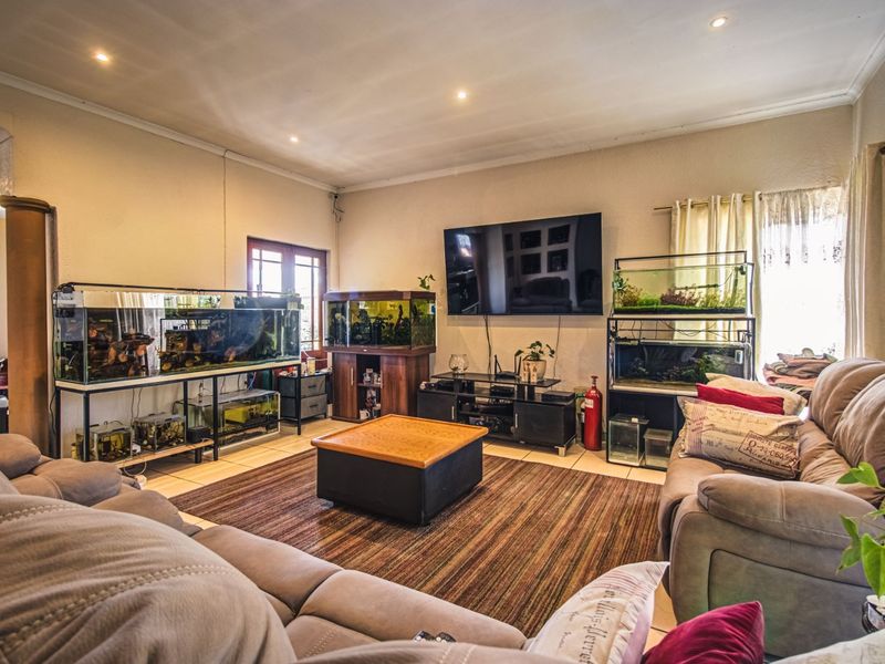 A spacious living room featuring tiled flooring, recessed downlighting, and coved cornicing, providing a functional base for a comfortable family lounge area.