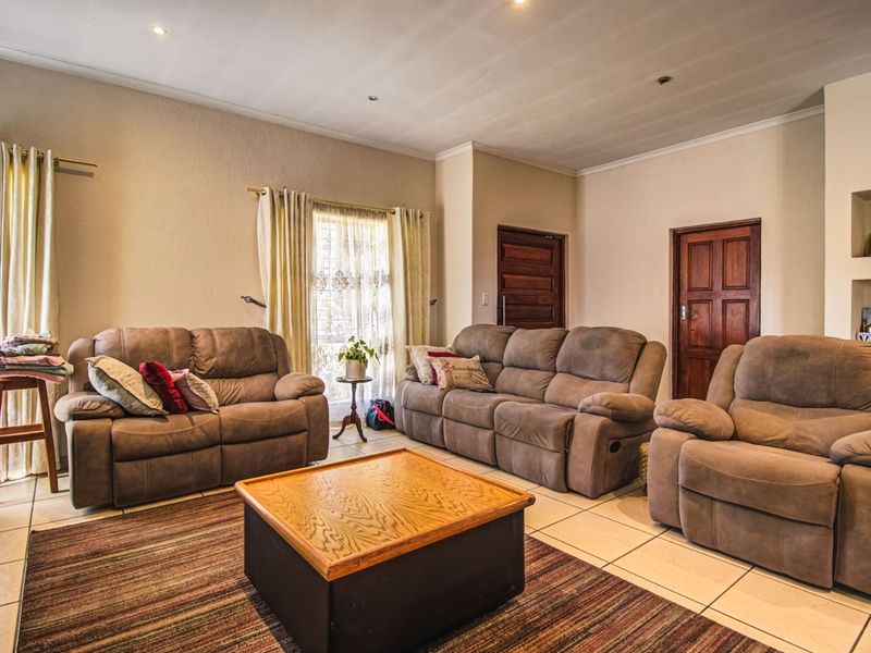 A spacious living room featuring tiled flooring, recessed downlighting, and classic wooden panel doors, offering a comfortable and functional layout.