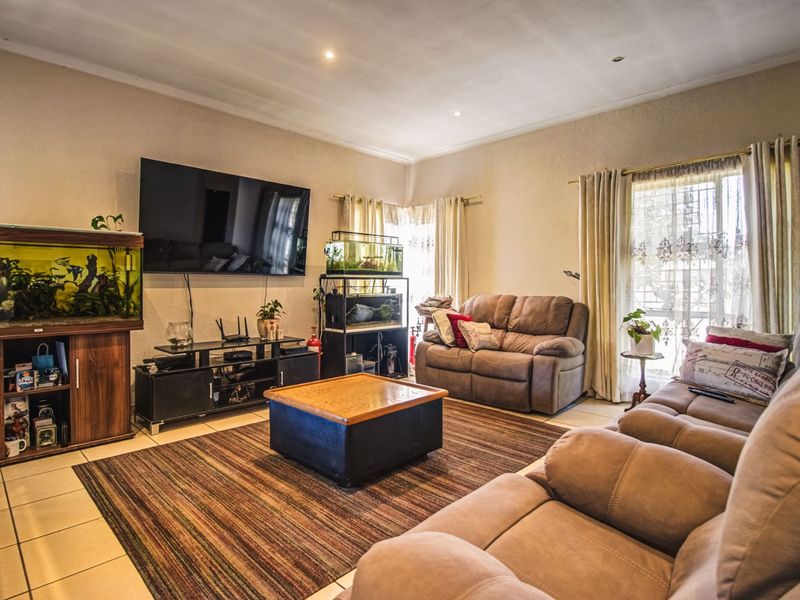 A comfortable living room featuring tiled flooring and recessed downlighting, providing a functional and well-lit space for relaxation.