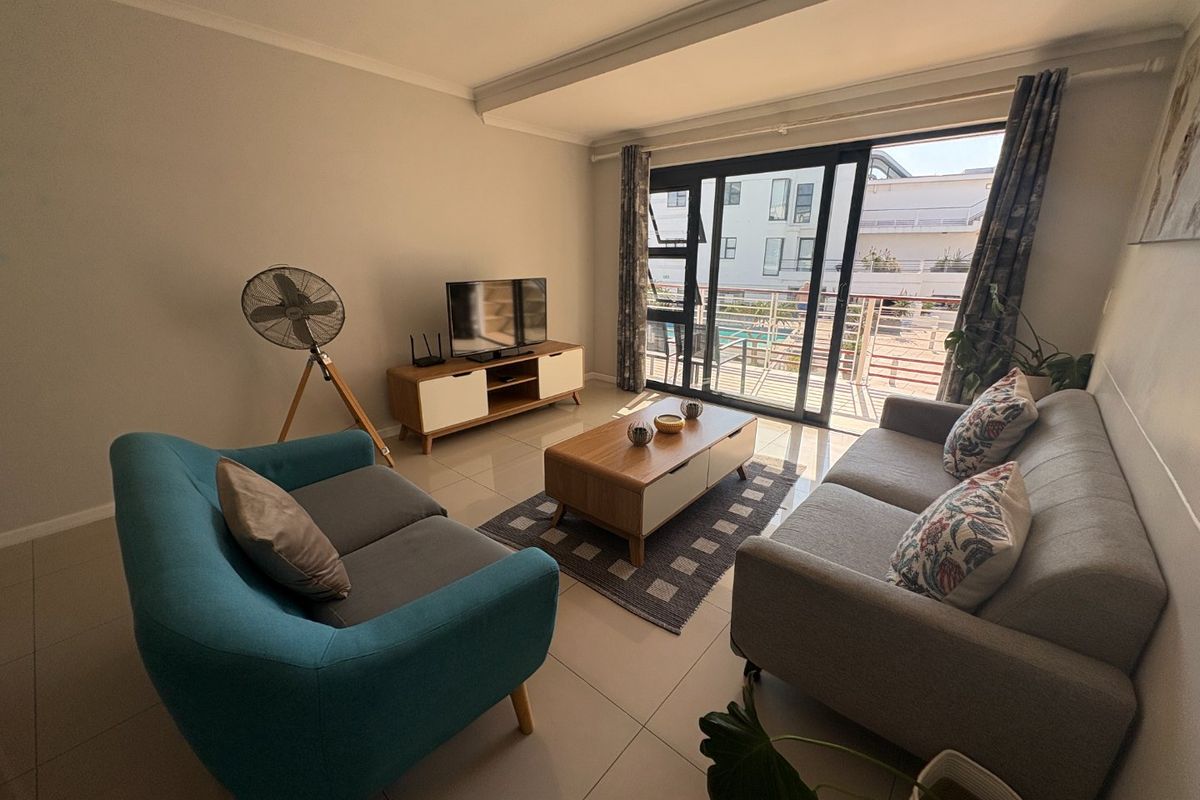 A bright living room featuring tiled flooring and large sliding glass doors that provide access to an outdoor balcony area.