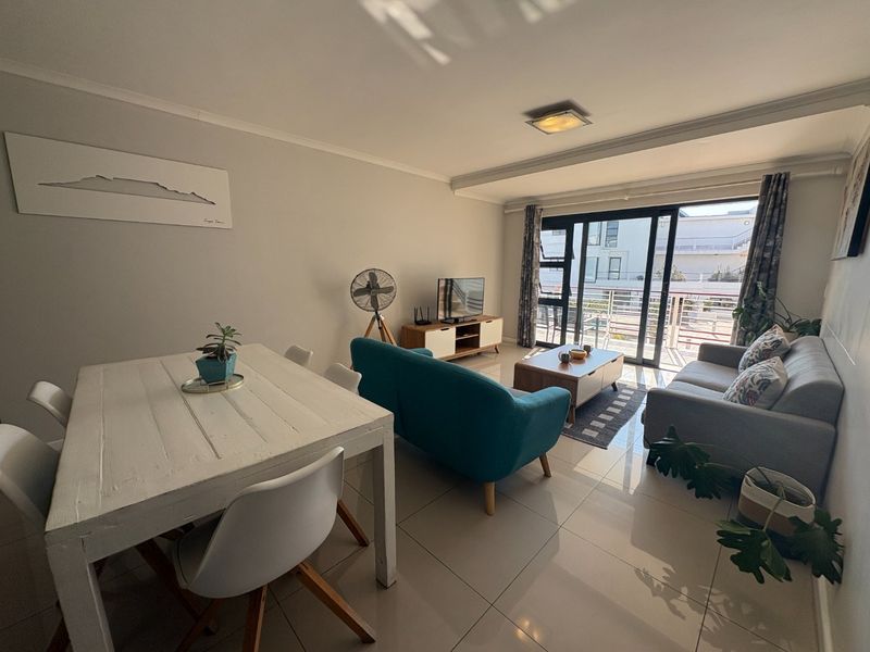 Bright open-plan living and dining area featuring tiled flooring and large sliding glass doors leading to a balcony.