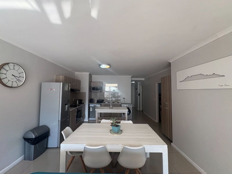 Open-plan kitchen and dining area featuring modern built-in cabinetry, integrated appliances, and neutral tiled flooring throughout the space.