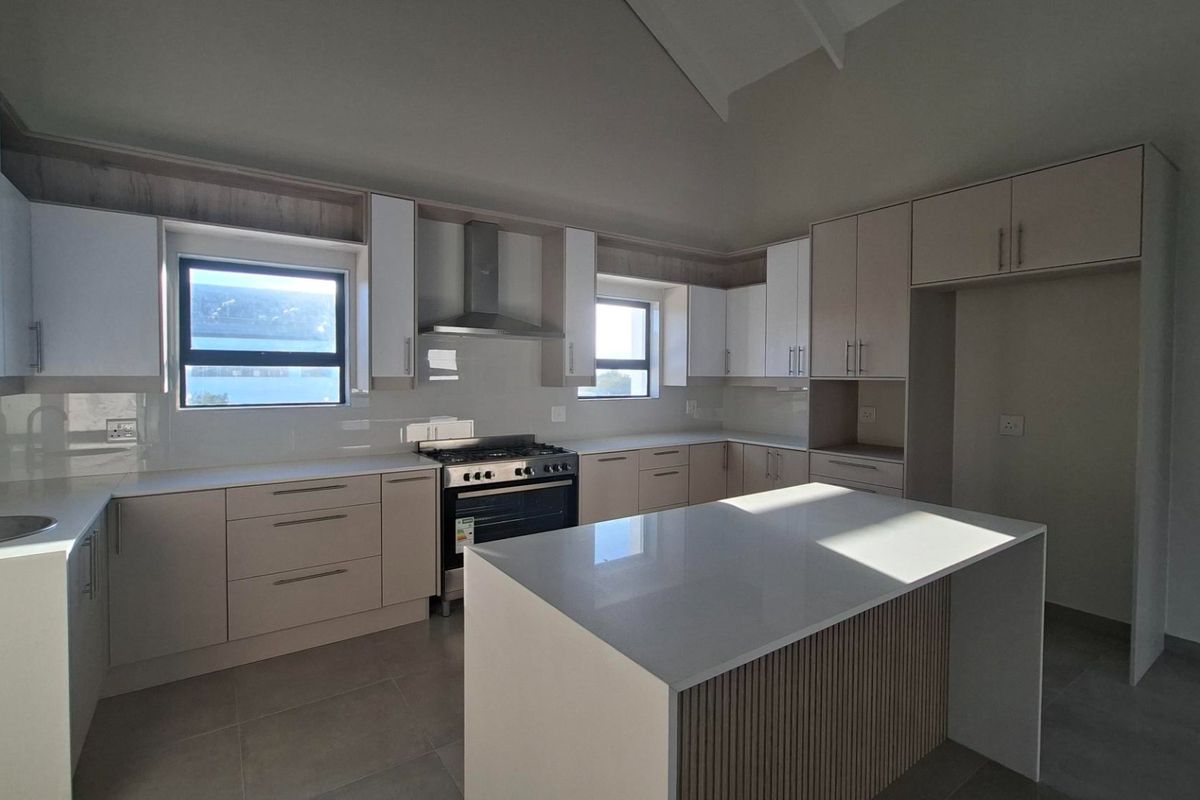 Modern kitchen featuring sleek cabinetry, stone countertops, a central island, and high-quality stainless steel appliances in a bright, open-plan space.