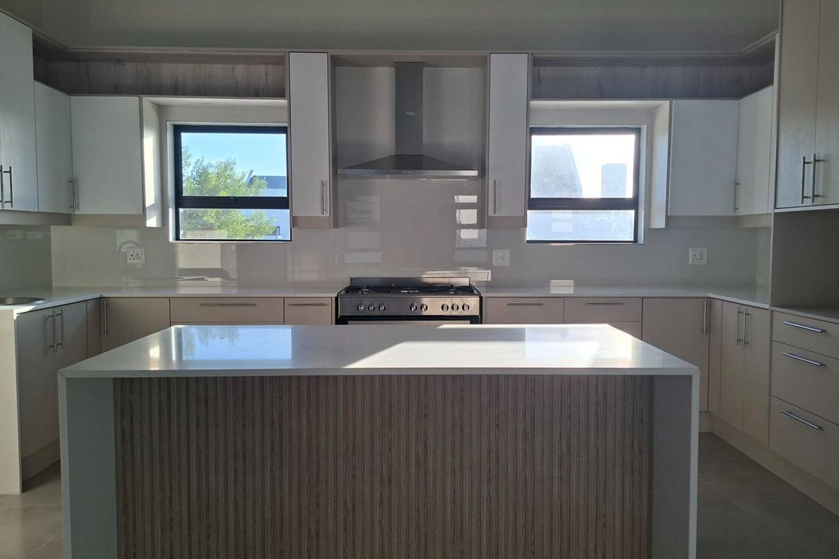 Modern kitchen featuring a central island, quartz countertops, stainless steel gas stove, extractor fan, and ample built-in cabinetry.