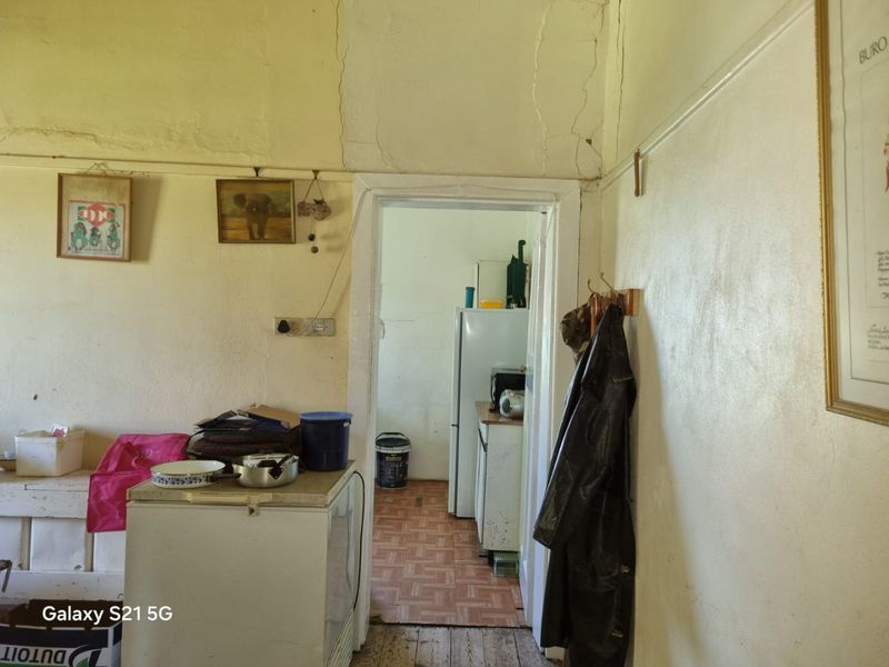 A view into a secondary kitchen or scullery area showing significant wear to wall finishes and plasterwork requiring maintenance and renovation.