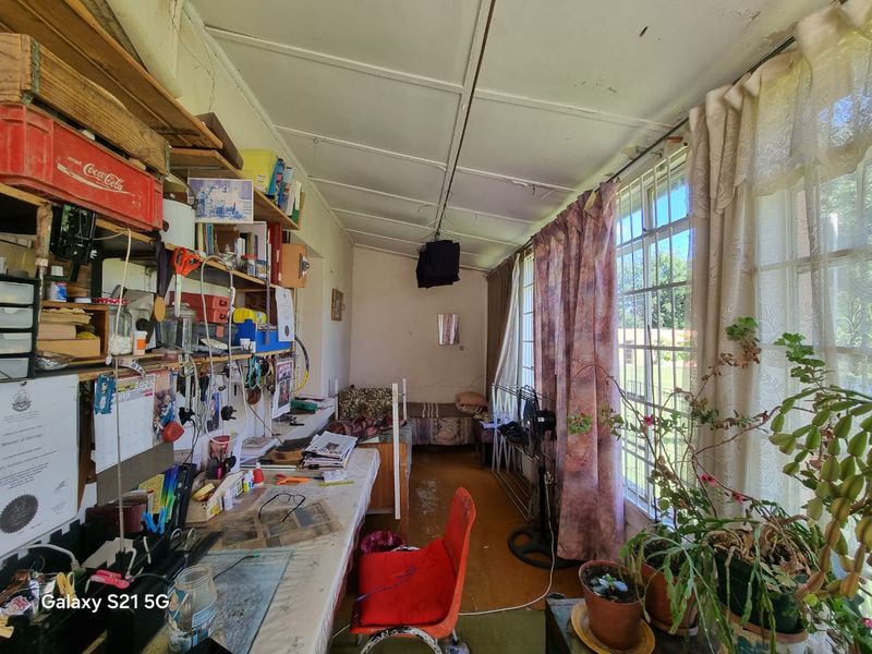 Enclosed patio area featuring large windows with security bars, built-in shelving, and tiled flooring, currently used as a workspace.