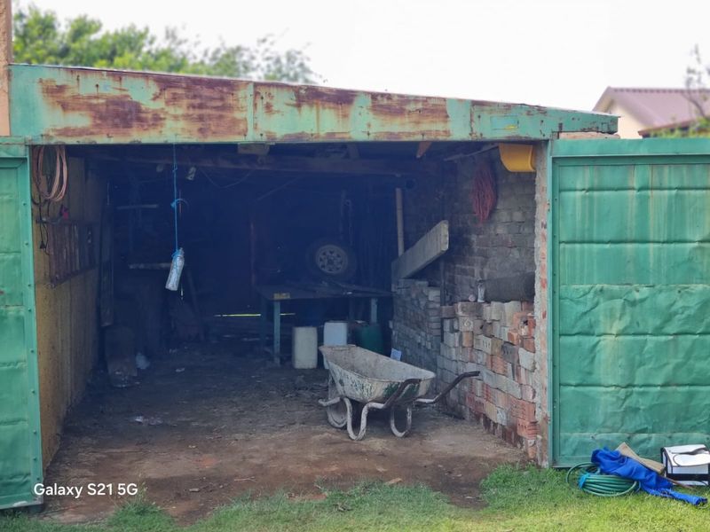 A detached garage structure featuring a metal roof and brick walls, currently in a state of significant disrepair and requiring structural maintenance.