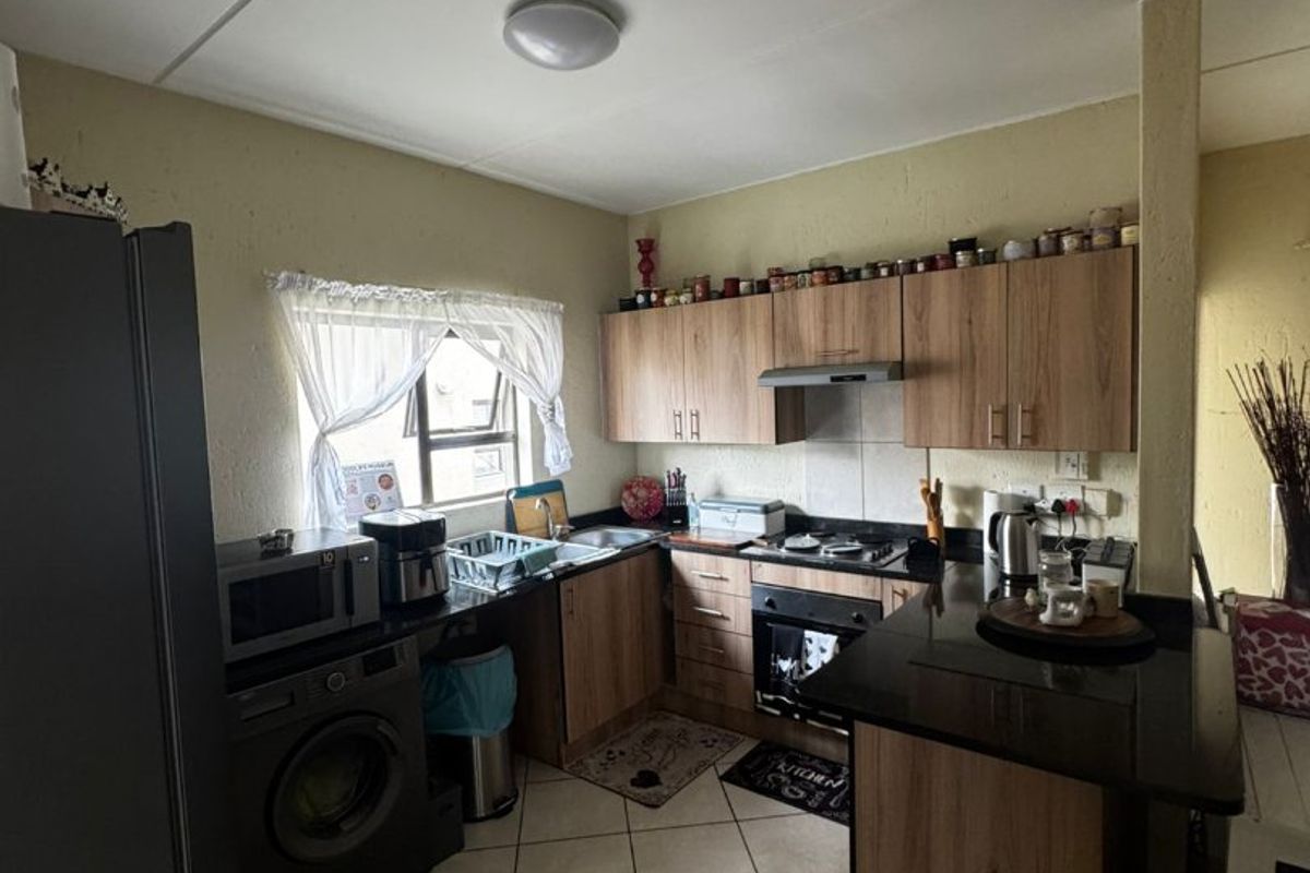 A functional kitchen featuring laminate cabinetry, granite countertops, built-in oven, hob, extractor fan, and tiled flooring.