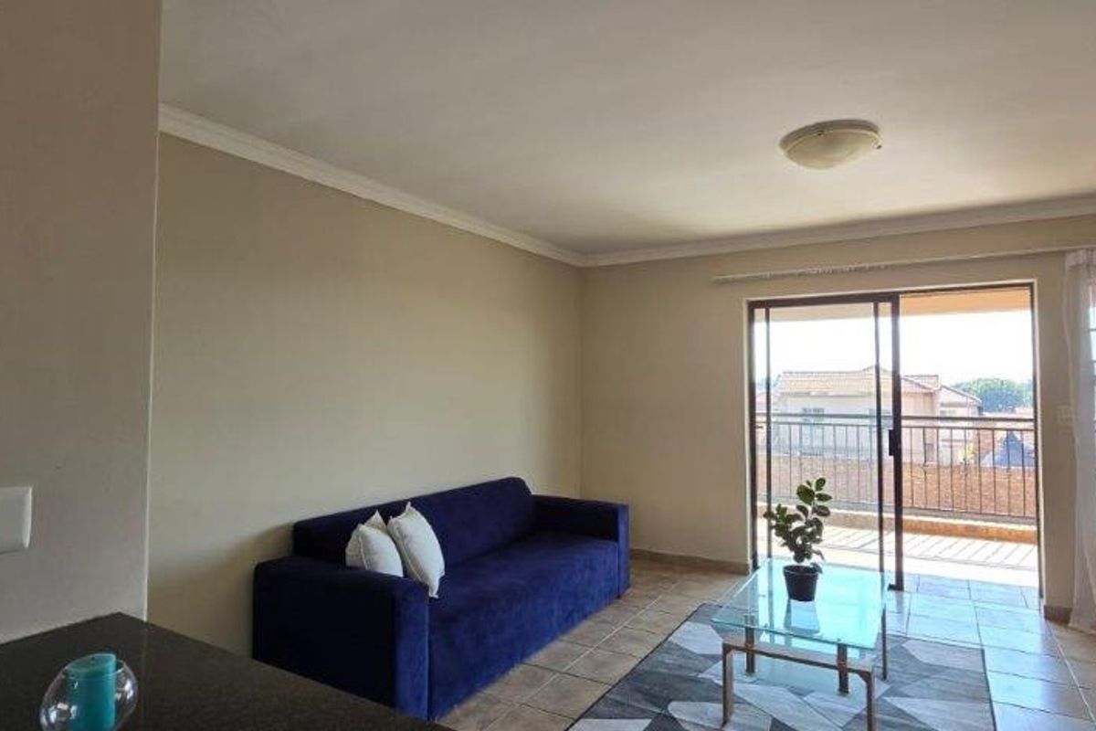 A bright living room featuring tiled flooring, neutral walls, and a sliding glass door providing access to an outdoor balcony area.