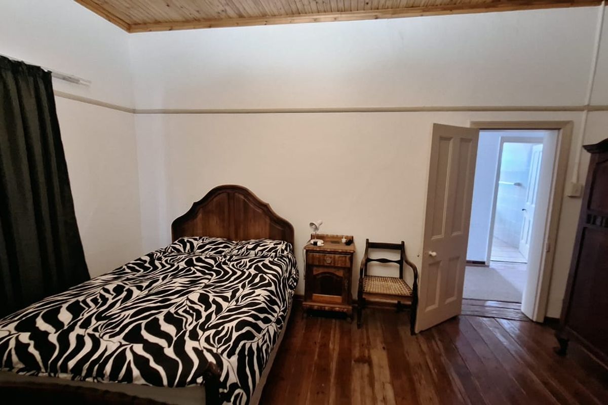 A bedroom featuring original timber flooring and a timber ceiling, with a doorway leading to an adjacent room.