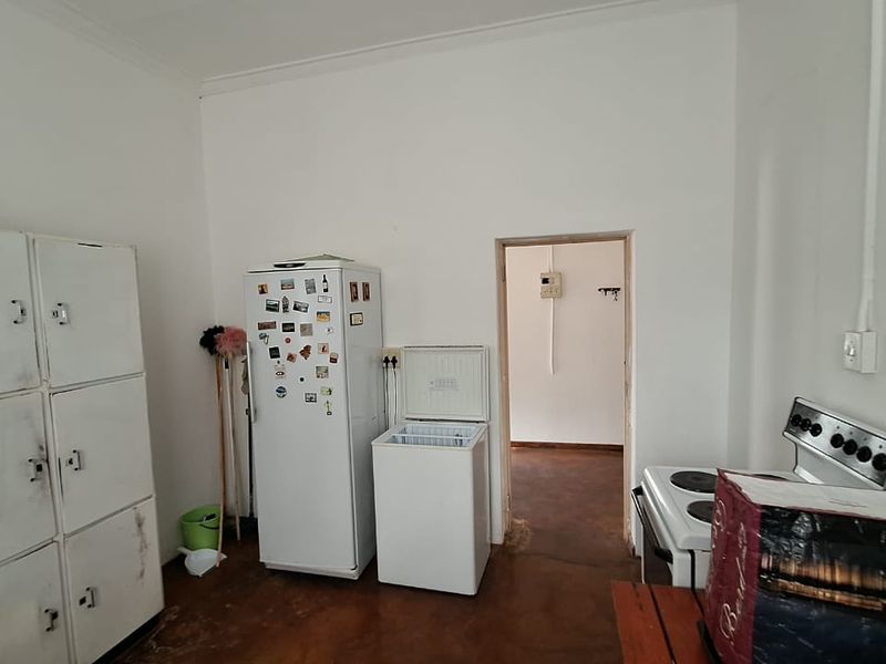 A functional scullery or utility area featuring built-in metal storage lockers, a freestanding stove, and durable concrete flooring.