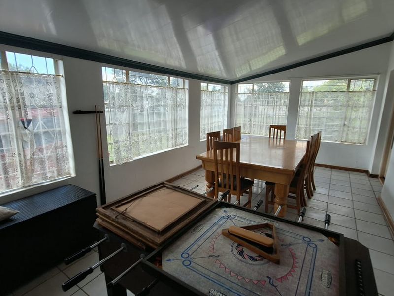 A bright dining room featuring large windows, tiled flooring, and a sloped ceiling, offering a spacious area for family meals and gatherings.