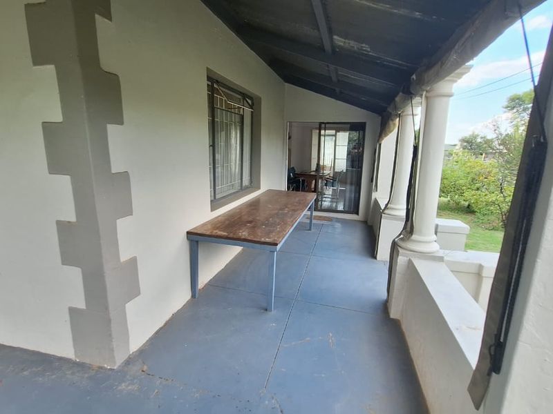A covered outdoor patio area featuring concrete columns, painted flooring, and direct access to the interior through a sliding glass door.