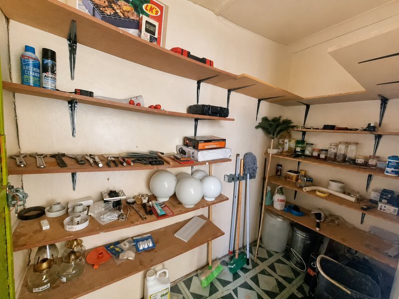 A utility or storage room featuring extensive wall-mounted shelving and patterned tiled flooring, suitable for use as a pantry or scullery area.