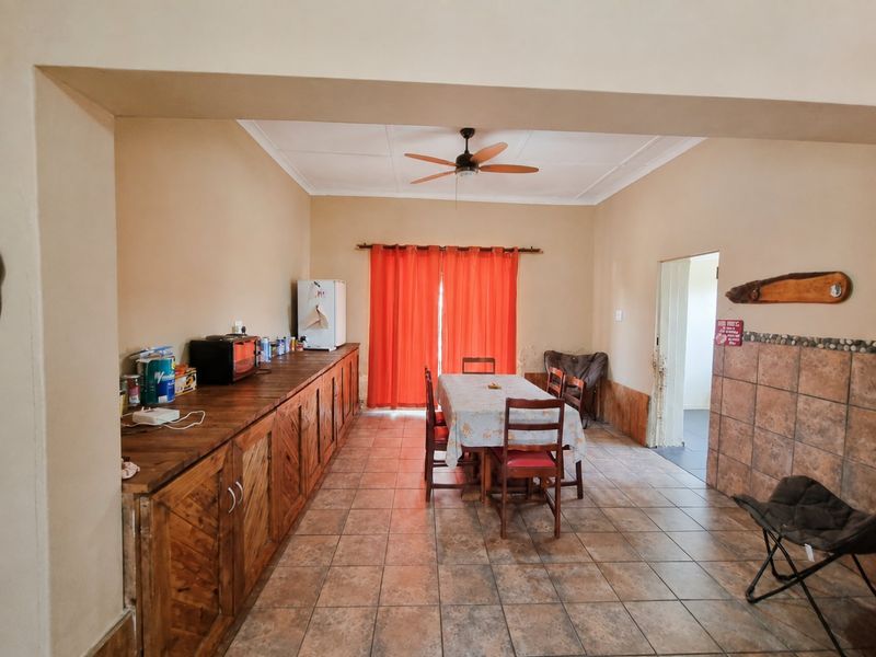 Open plan dining area featuring tiled flooring, a ceiling fan, and extensive built-in wooden cabinetry providing ample storage space.