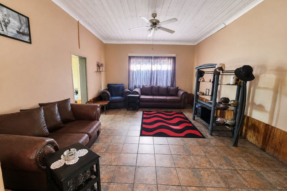 Spacious living room featuring tiled flooring, timber wall paneling, and a timber ceiling with a central fan.