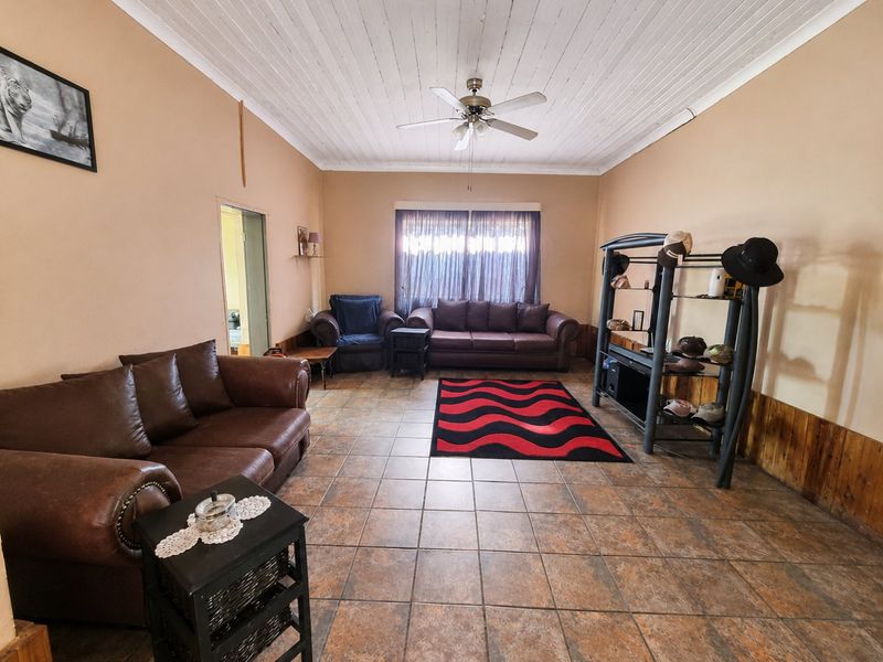 Spacious living room featuring tiled flooring, timber wall paneling, and a timber ceiling with a central fan.
