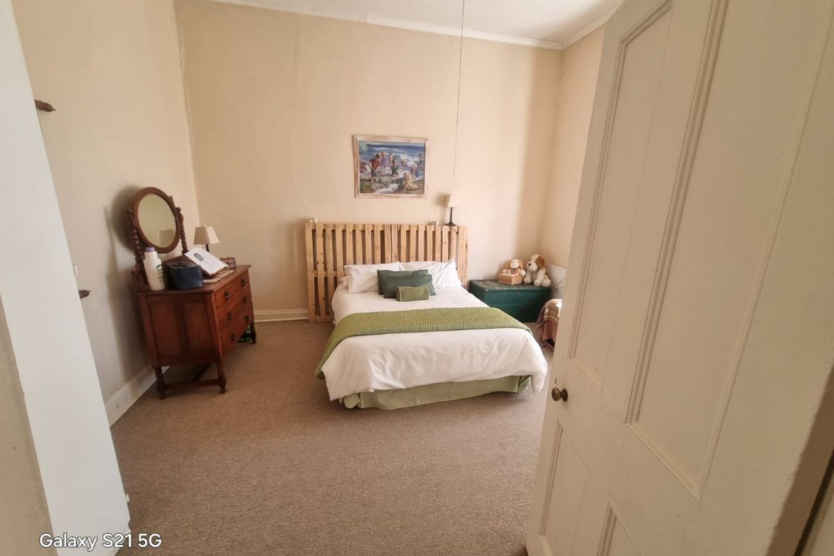 A bedroom featuring neutral wall tones and carpeted flooring, requiring cosmetic updates to the wall finishes to improve the overall aesthetic.