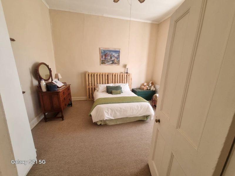 A bedroom featuring neutral wall tones and carpeted flooring, requiring cosmetic updates to the wall finishes to improve the overall aesthetic.