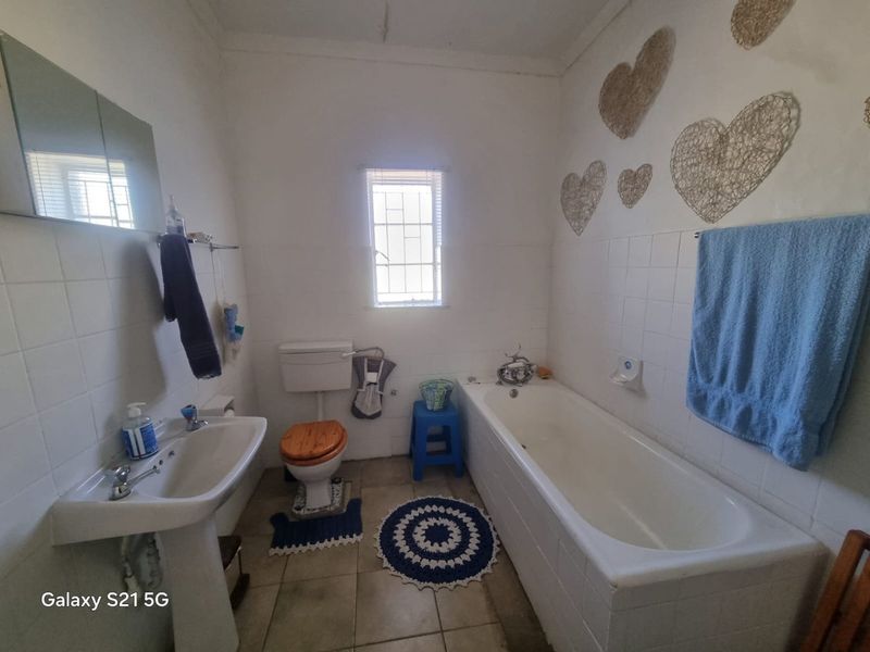 A functional bathroom featuring a pedestal basin, toilet, and bathtub with tiled finishes, offering potential for modernization and aesthetic updates.
