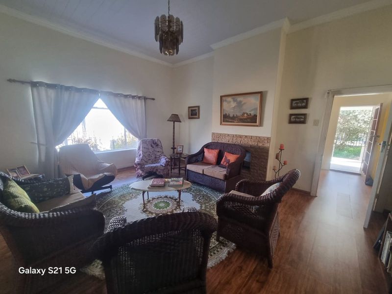 A cozy living room featuring a stone-surround fireplace, laminate flooring, and classic coved cornicing, offering a comfortable and traditional living space.