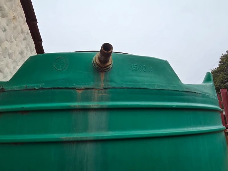 A 4500-liter green plastic water storage tank located in the exterior utility area of the property.