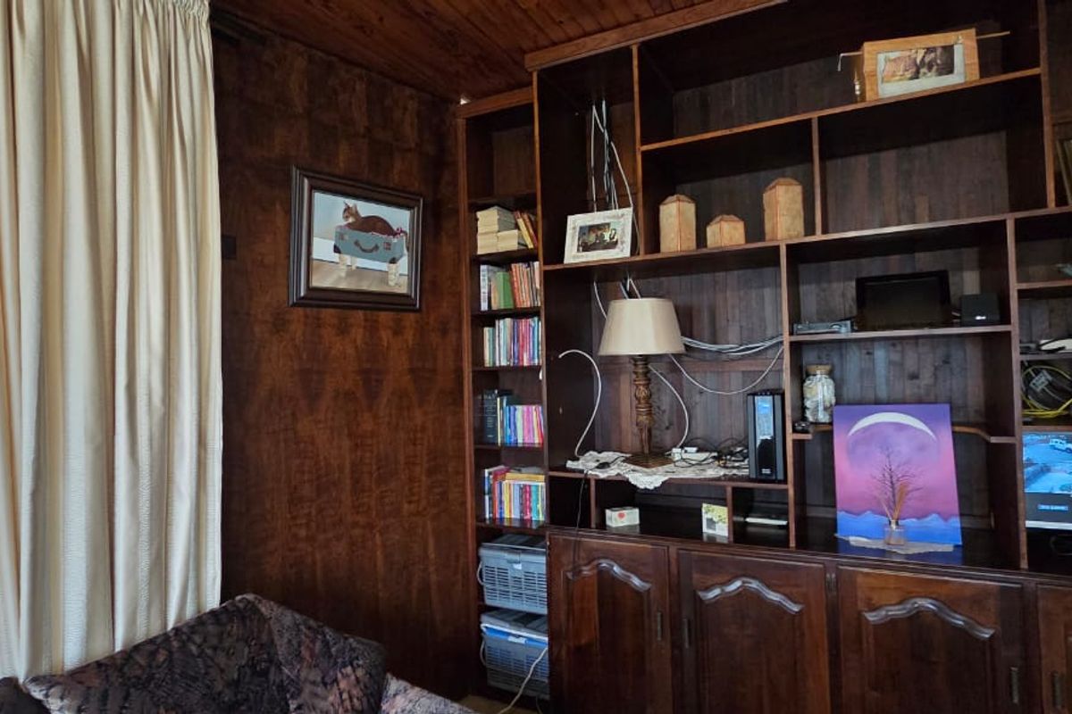 Living area featuring extensive built-in dark wood cabinetry and shelving with timber ceiling finishes, offering significant potential for a modern aesthetic update.