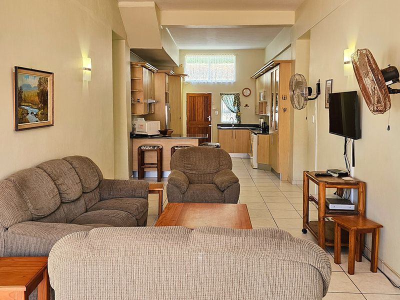 Open-plan living and kitchen area featuring tiled flooring, built-in cabinetry, and a breakfast counter, providing a functional and connected living space.