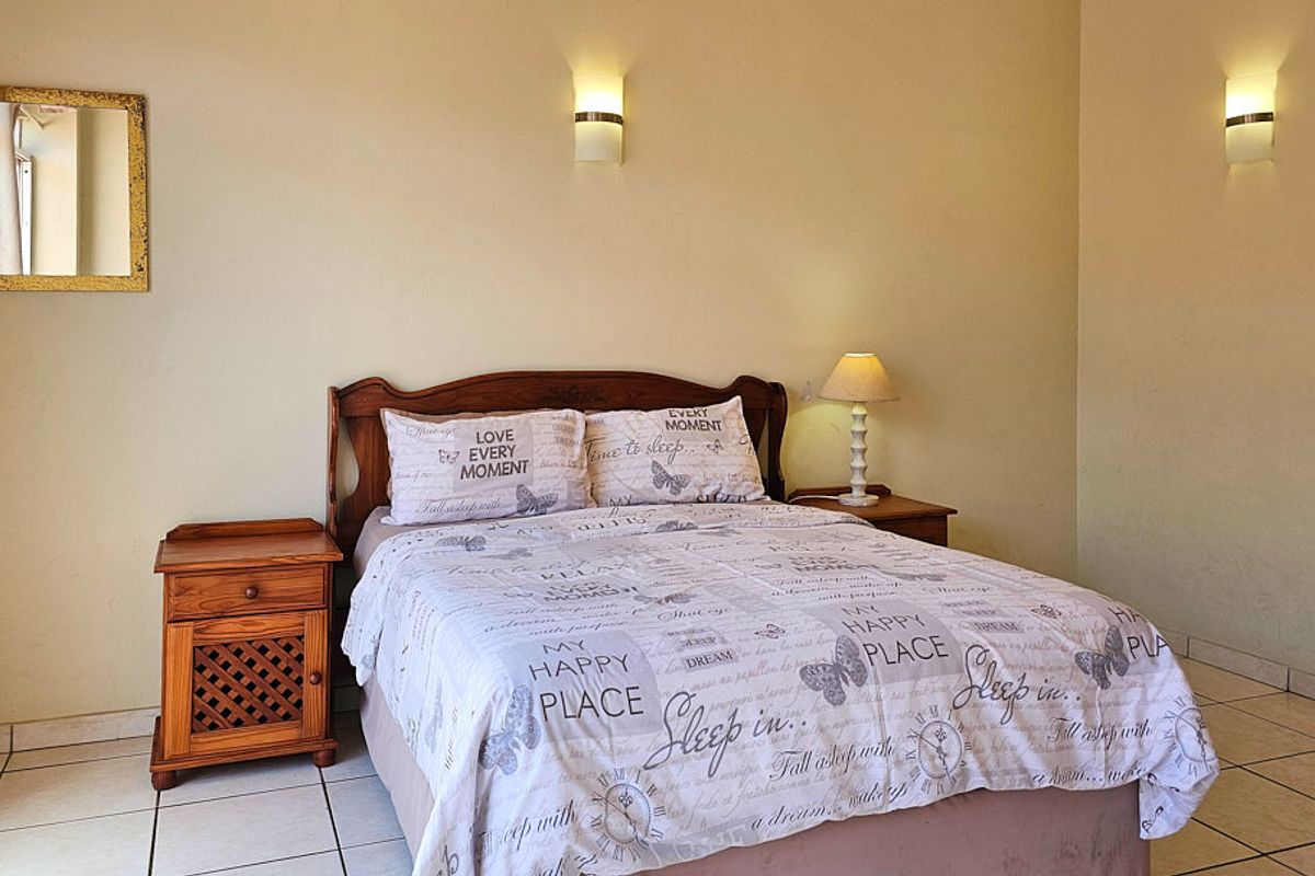 A bedroom featuring tiled flooring and dual wall-mounted light fixtures, providing a functional and neutral space.