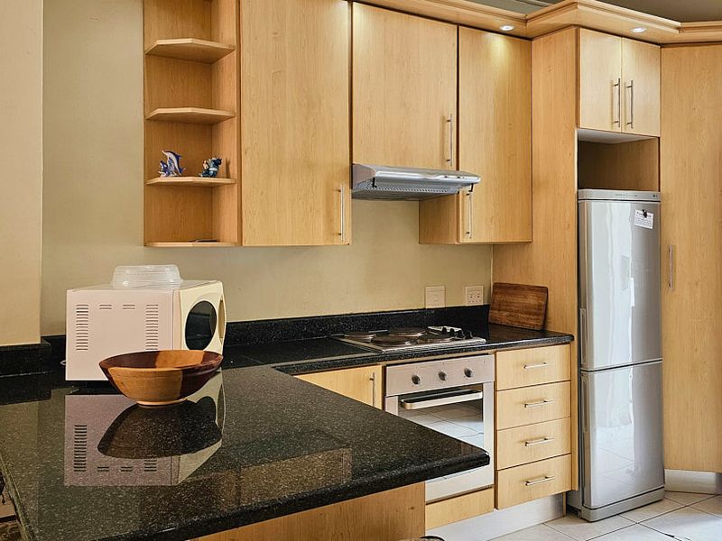A functional kitchen featuring light wood cabinetry, granite countertops, a built-in oven, and an electric hob, providing a practical workspace.