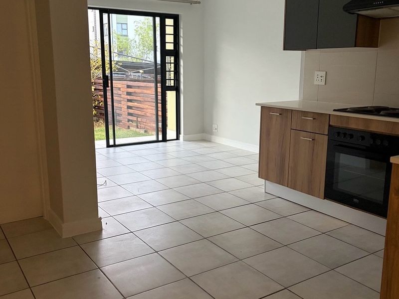 Open plan kitchen and living area featuring tiled floors, modern cabinetry, built-in appliances, and a sliding door leading to an outdoor space.