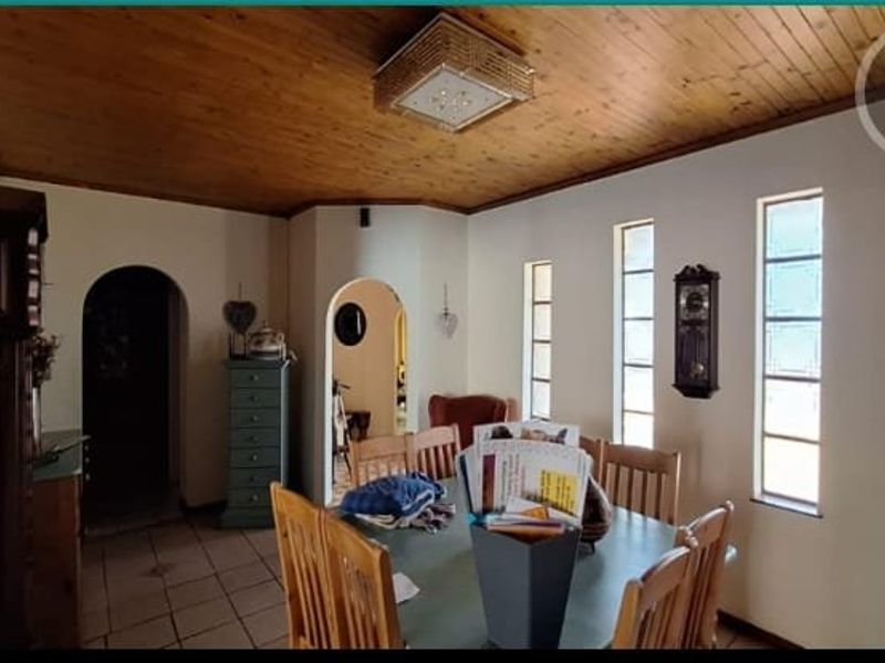 Dining room featuring a timber tongue and groove ceiling, tiled flooring, and arched doorways leading to adjacent living spaces.