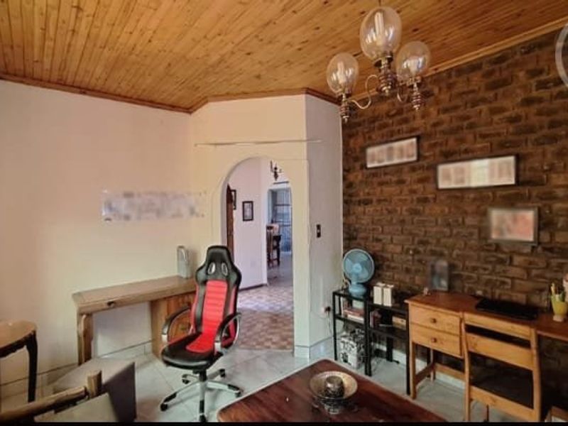 Living area featuring a rustic exposed brick feature wall, warm timber ceiling, and an arched entryway leading to adjacent spaces.