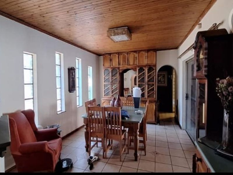 Dining room featuring a timber ceiling, tiled flooring, and built-in wooden cabinetry, connected to the rest of the home via an archway.