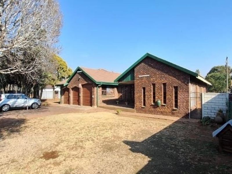A single-story face brick house featuring a double garage, paved driveway, and a large front lawn area.