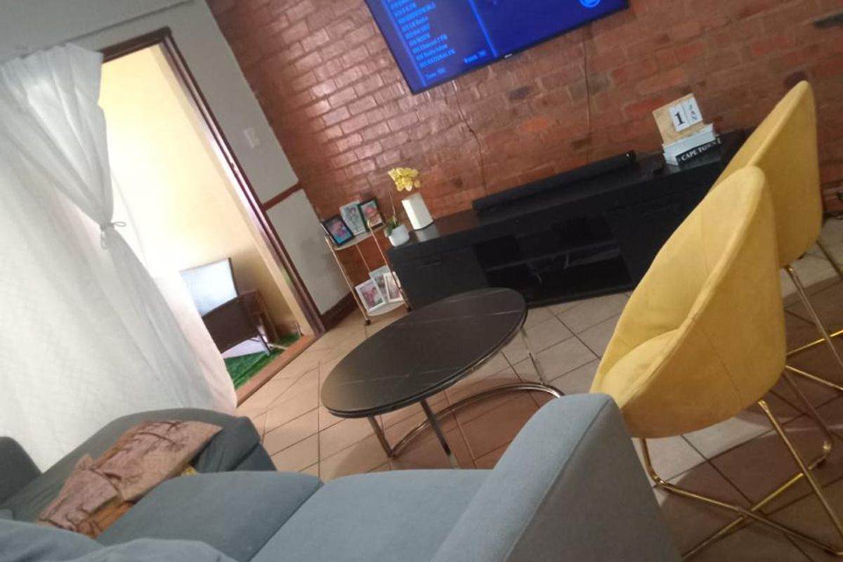 A living room featuring an exposed brick feature wall and ceramic floor tiles, providing a textured backdrop for the living space.