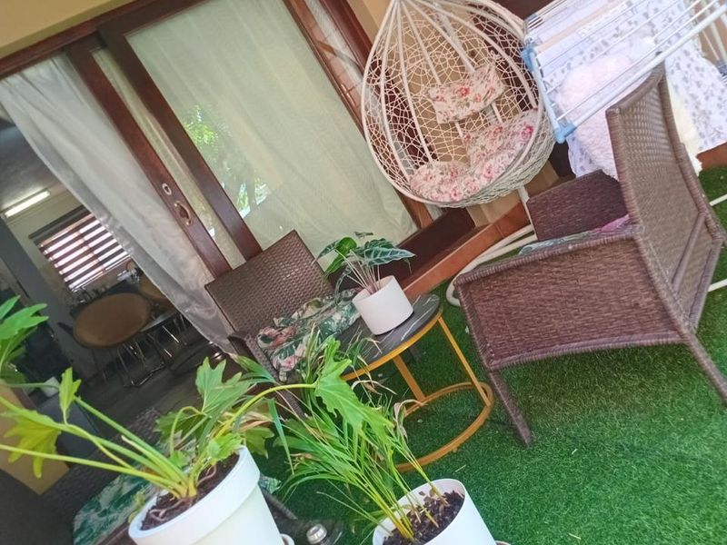 A covered balcony area featuring artificial grass flooring and large sliding glass doors providing access to the interior living space.