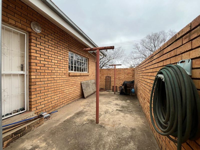 A rear exterior courtyard featuring brick walls, concrete paving, and fixed washing line poles, providing a functional utility space.