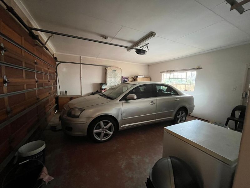 A functional garage space featuring a sectional door, concrete flooring, and overhead lighting, providing secure parking and additional storage capacity.