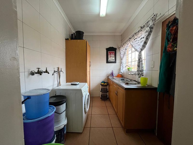 Functional laundry room featuring tiled walls, built-in cabinetry, a stainless steel sink, and dedicated plumbing connections for appliances.