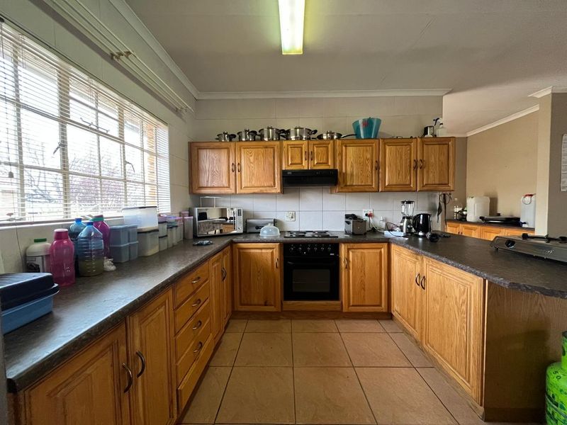 A functional kitchen featuring traditional wooden cabinetry, laminate countertops, built-in oven, and hob, with ample natural light from a large window.