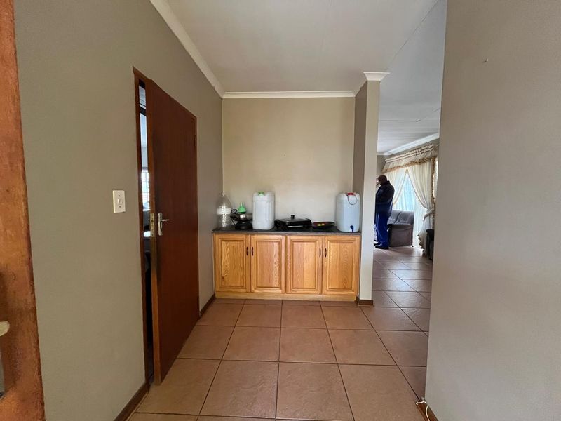 A tiled hallway featuring built-in wooden cabinetry, providing a functional transition space between the living area and other rooms in the apartment.