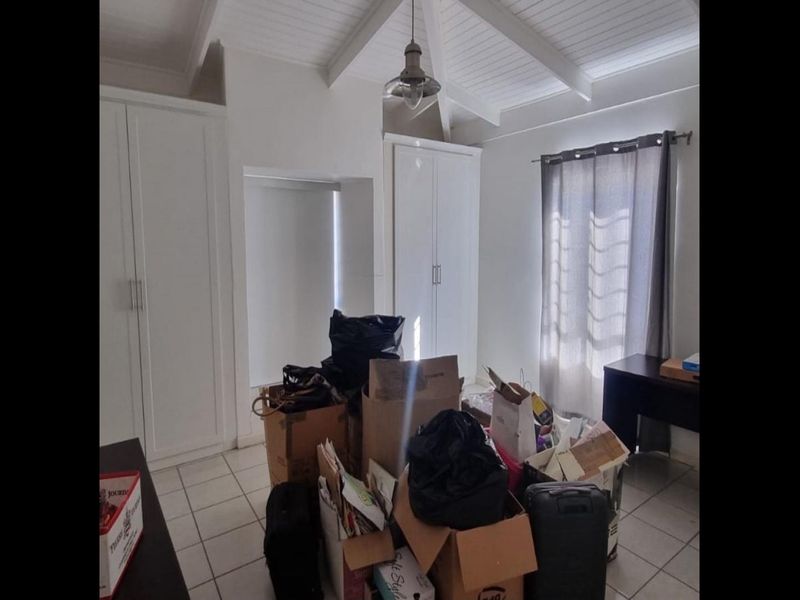 Bedroom featuring vaulted ceilings, tiled flooring, and built-in cupboards, offering a bright and functional space.