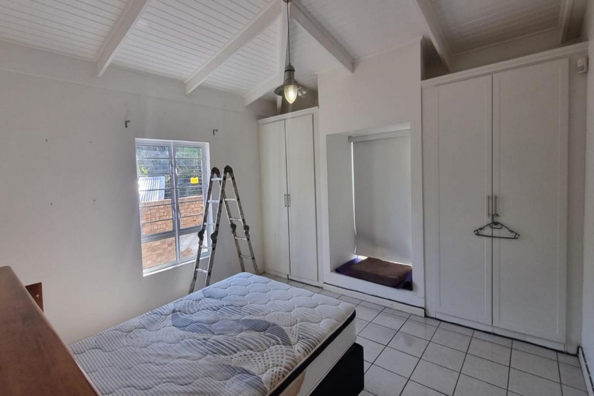 A bedroom featuring a vaulted ceiling, tiled flooring, built-in cupboards, and a built-in window seat area.