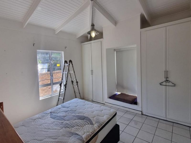 A bedroom featuring a vaulted ceiling, tiled flooring, built-in cupboards, and a built-in window seat area.